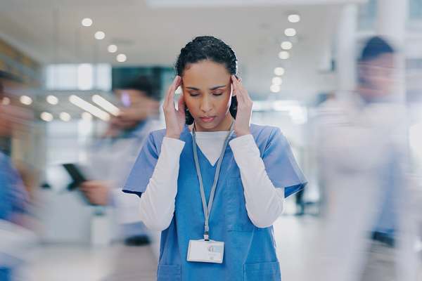 Nurse with hands on her head, looking overwhelmed
