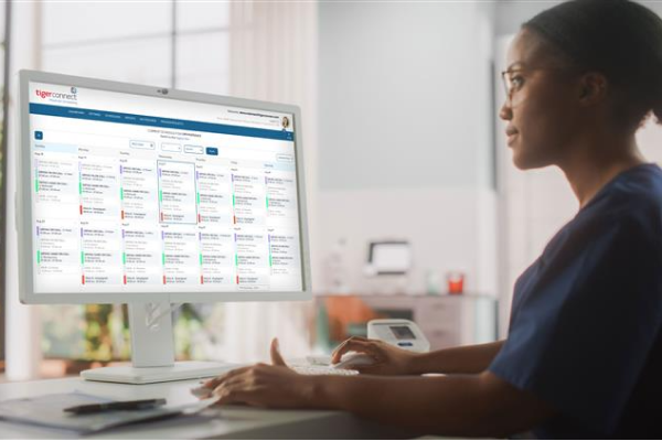 Clinician looking at a PC showing the TigerConnect Scheduling UI